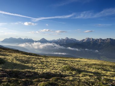 Mountain meadow with view of cloudy mountains and blue sky