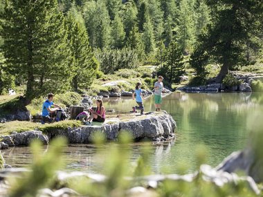 Children relaxing and playing by a clear mountain lake in summer